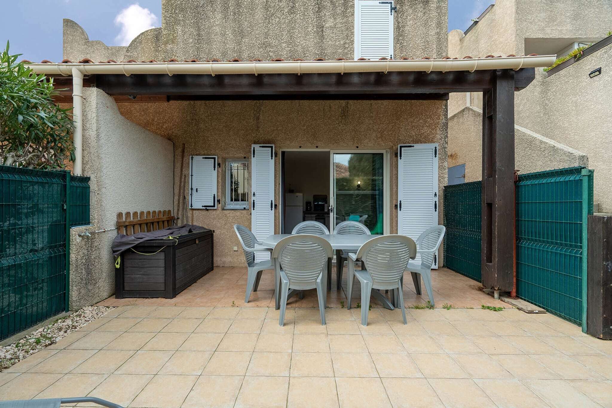 A patio area with a table and chairs, a covered seating area, and a green fence.