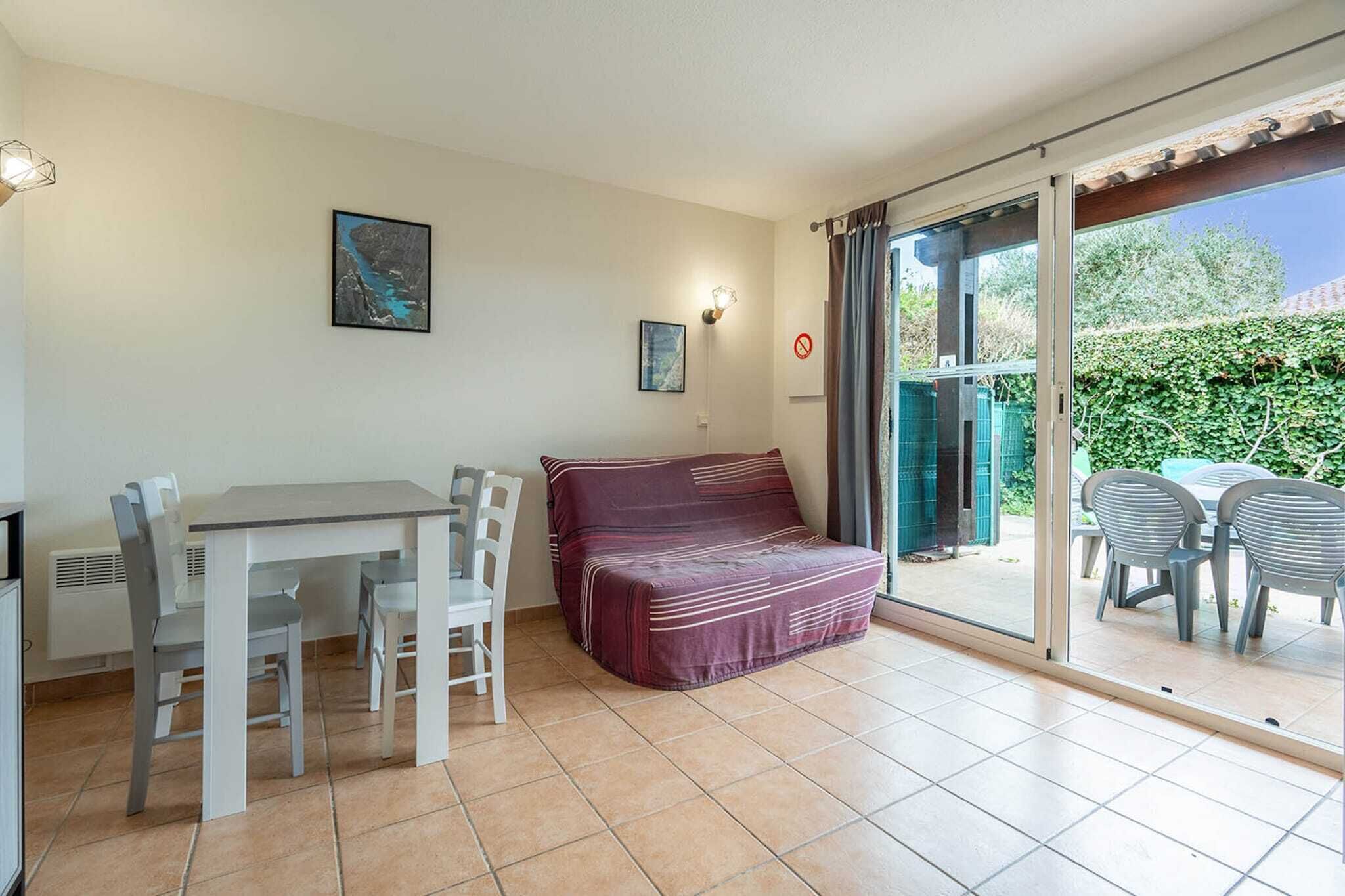 Une pièce comprenant une table à manger, des chaises, un canapé et une porte-fenêtre coulissante donnant sur un espace extérieur avec une table et des chaises.