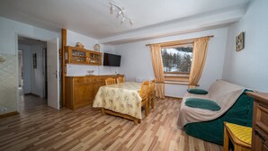 Una habitació acollidora amb taula de dinar de fusta, cadire, sofà i televisió.