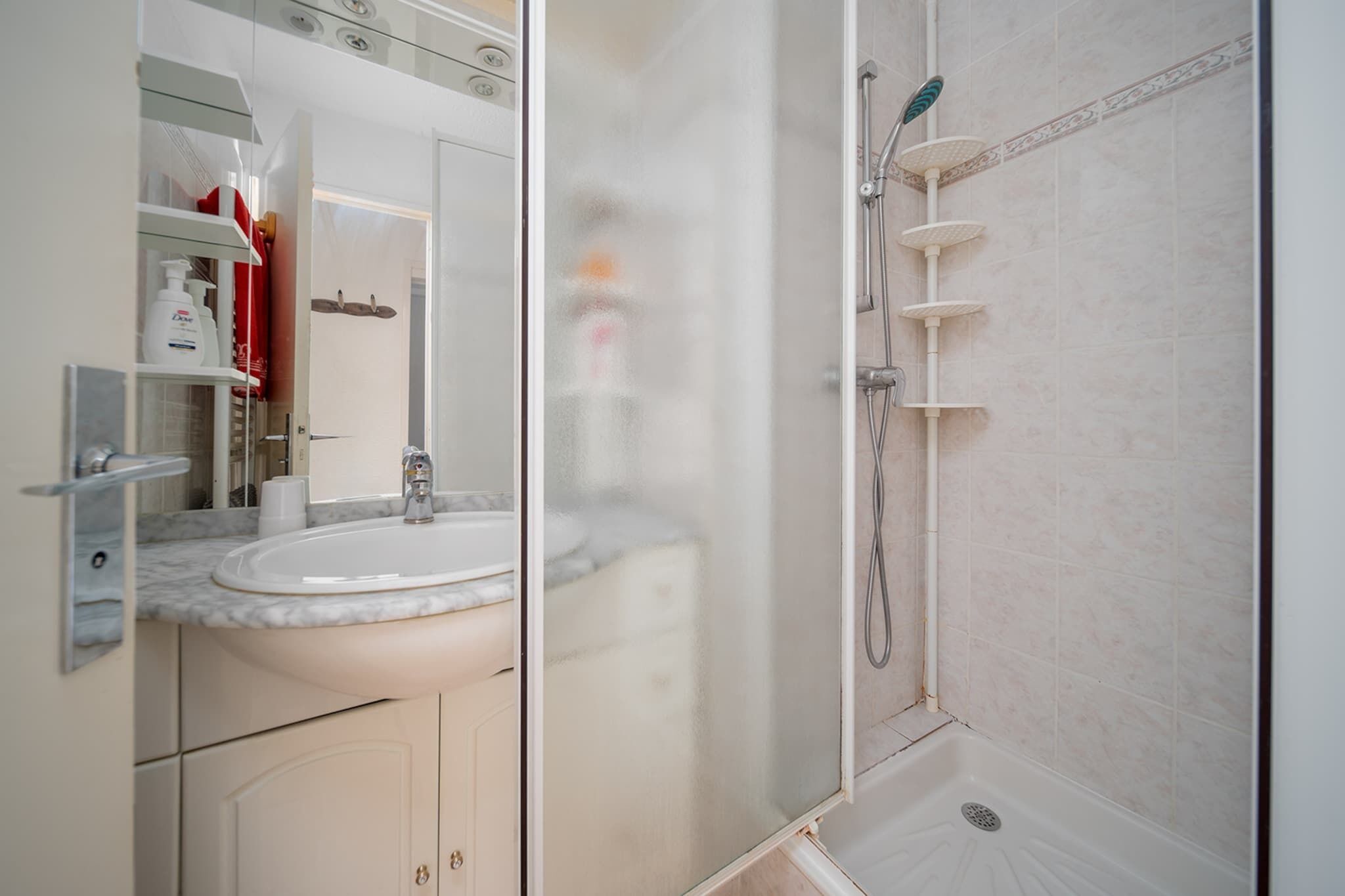 Een badkamer met een marmeren wastafel, een glazen douchecabine en een toilet.