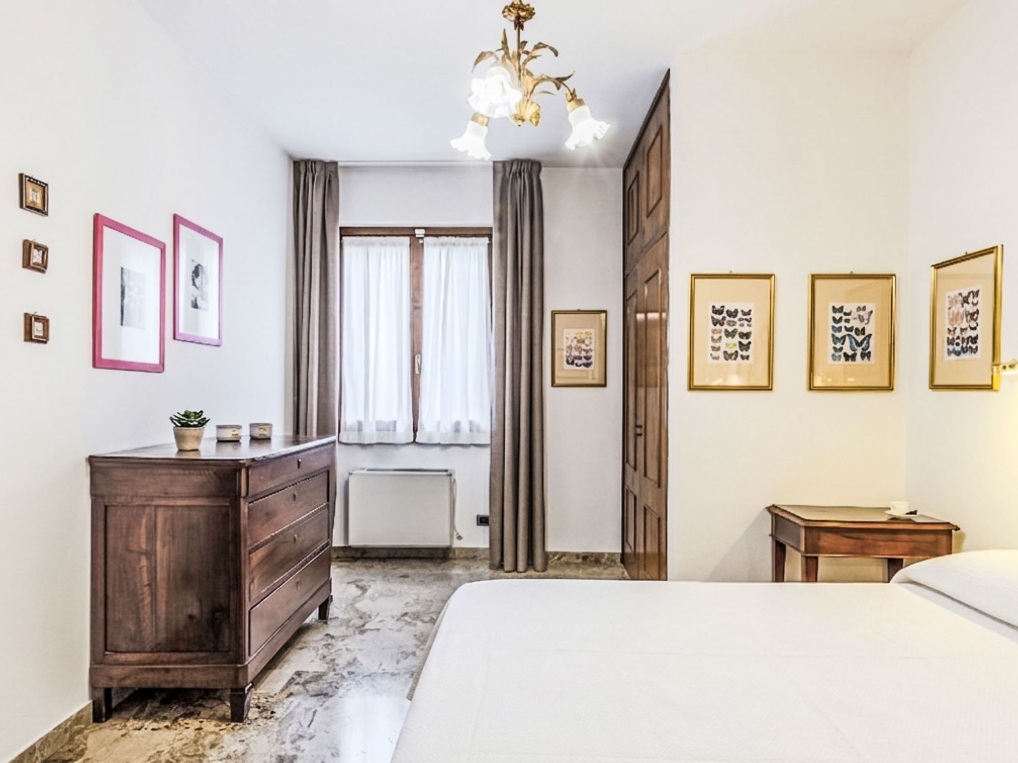 A bedroom with a bed, dresser, and artwork on the walls.