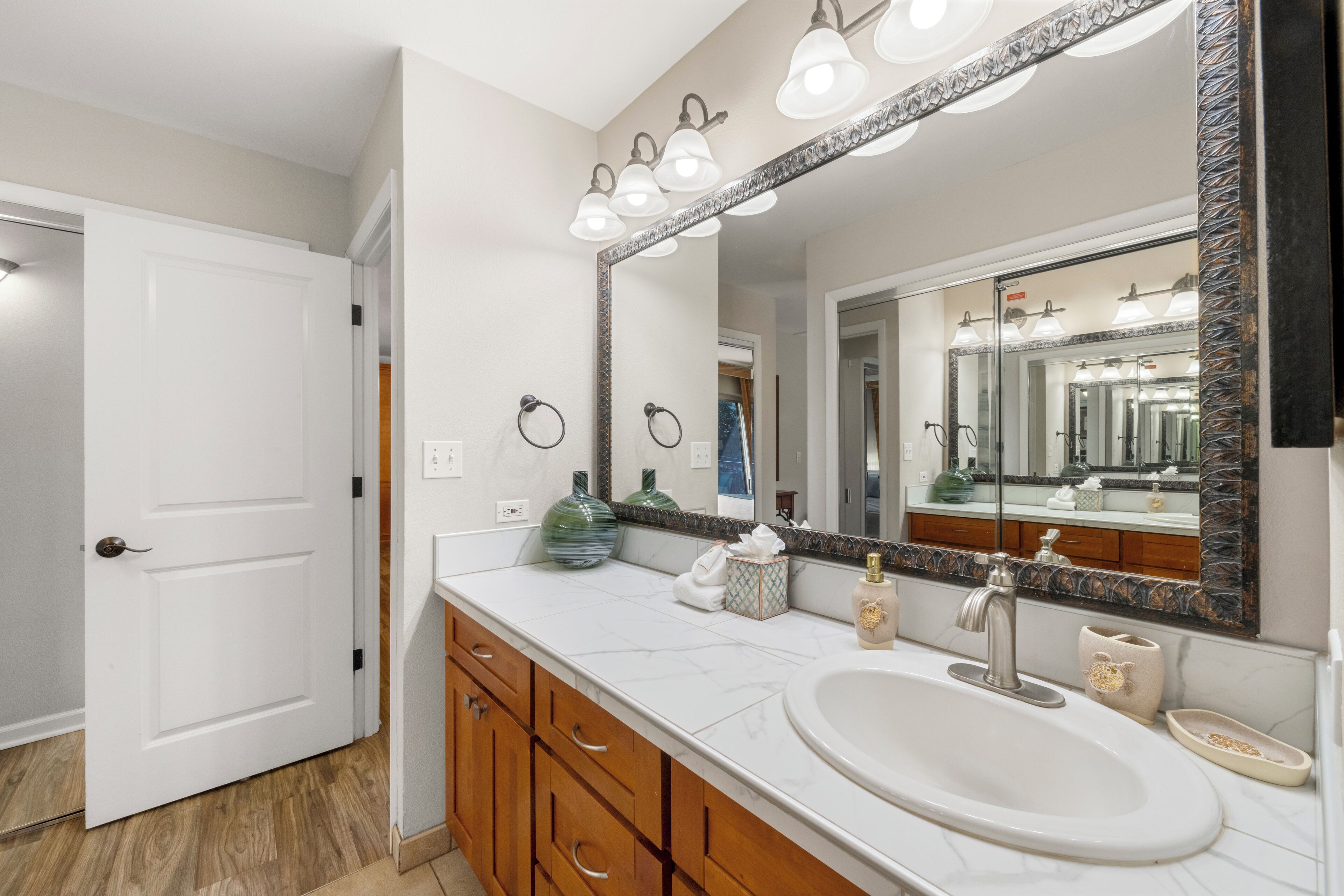 A bathroom with a large mirror, a sink, and wooden cabinets.