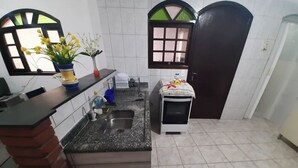 Uma cozinha com bancada de granito, pia, fogão e janela com moldura decorativa.