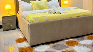 A neatly made bed with striped bedding, a headboard, and two bedside lamps.