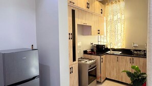 A modern kitchen with stainless steel appliances, wooden cabinets, and a tiled floor.
