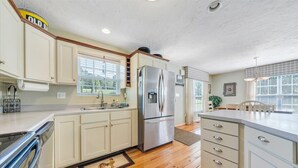 Una cocina con armarios blancos, electrodomésticos de acero inoxidable y piso de madera.