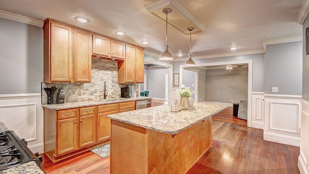 A kitchen with wooden cabinets, granite countertops, and a central island.