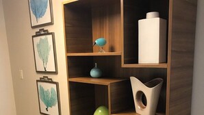 Un pasillo con un aparador de madera que contiene diversos objetos decorativos y obras de arte enmarcadas en la pared.