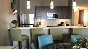 Una cocina moderna con una isla central, taburetes de bar e iluminación colgante.
