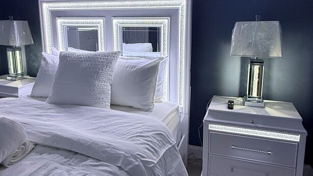 Un dormitorio con una cama grande, dos mesitas de noche y un espejo montado en la pared.