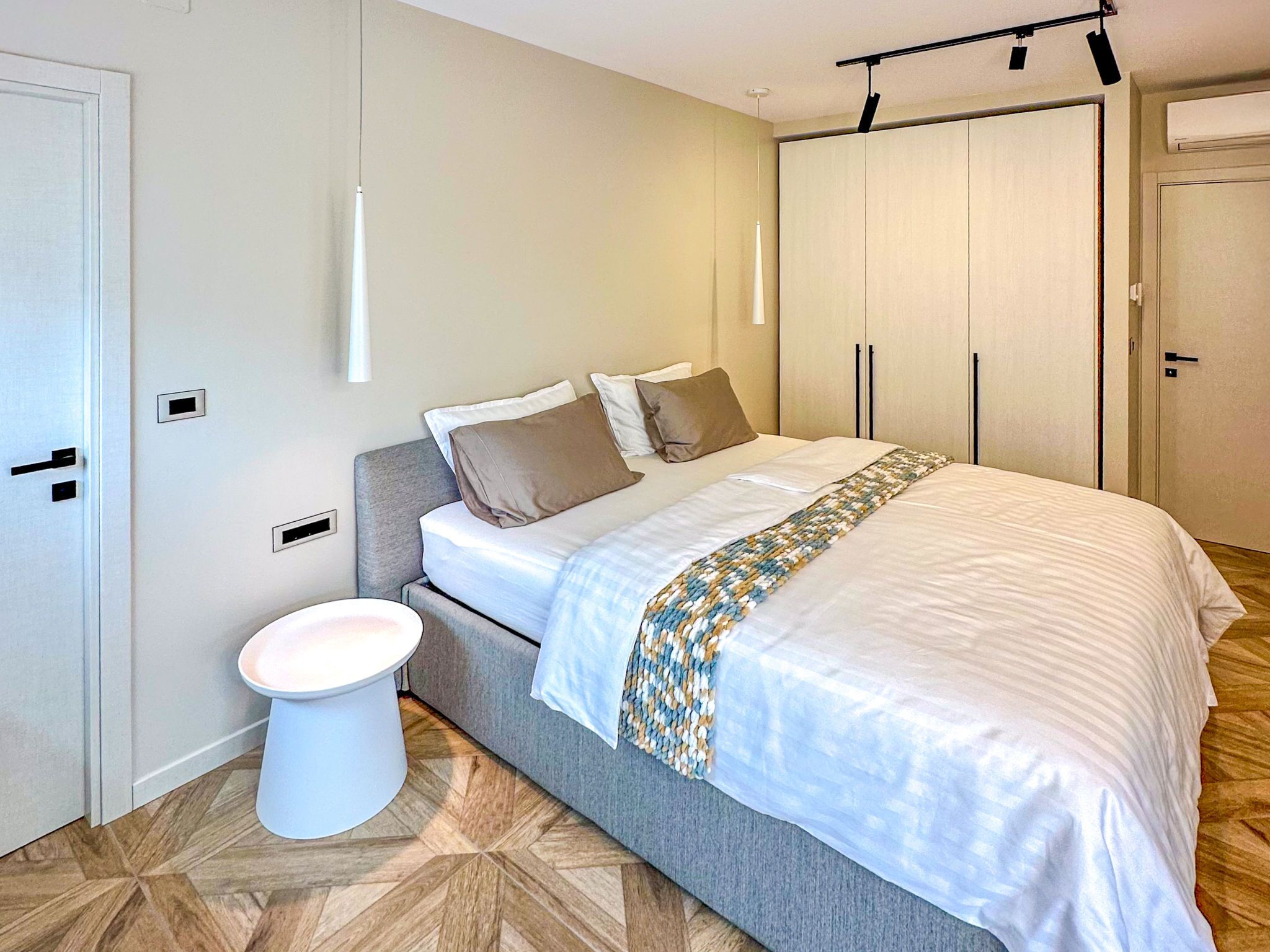 A bedroom with a bed, a bedside table, a wardrobe, and a toilet.