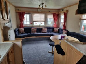 A cozy RV interior with a curved sofa, a small kitchen area, and a dining table.