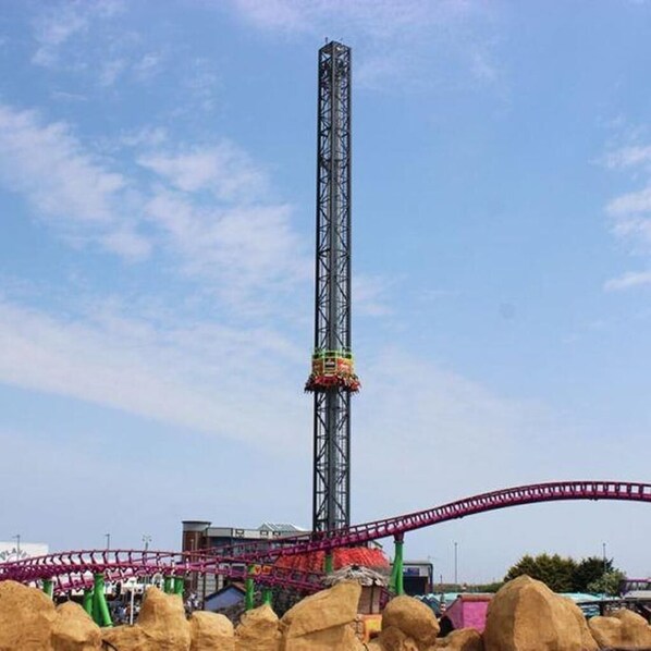 A tall metal tower with a roller coaster track at the base.