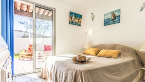 A bedroom with a bed, a chair, a table, and a view of the outside. - Domaine Grand Plage by Interhome (Cap d'Agde)