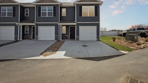 A modern multi-story residential building with three garage doors, a concrete driveway, and a well-maintained lawn. - Raceday Getaway, 3BR/2.5BA home right across from Bristol Motor Speedway! (Bristol)