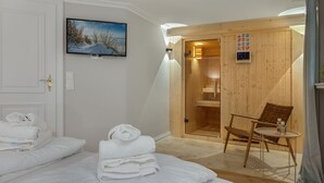 A hotel room with two beds, a sauna, a wooden chair, and a painting on the wall. - Haus Kamp - Exclusive thatched house for 6 pers. with sauna, fireplace, garden, car (Kampen (Sylt))