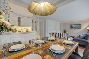Comedor con mesa de madera dispuesta para seis personas, armarios blancos y una lámpara colgante moderna.
