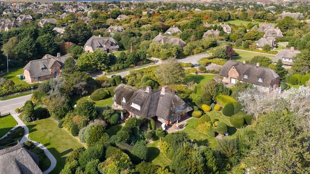 A residential area with houses surrounded by lush greenery and a clear view of the sea. - Haus Kamp - Exclusive thatched house for 6 pers. with sauna, fireplace, garden, car (Kampen (Sylt))