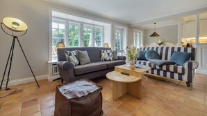 A living room with two sofas, a coffee table, and a floor lamp. - Haus Kamp - Exclusive thatched house for 6 pers. with sauna, fireplace, garden, car (Kampen (Sylt))