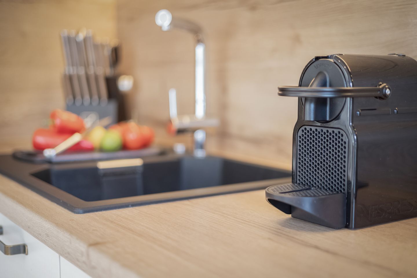 Eine Küche mit Spüle, Schneidebrett mit Gemüse und einer Kaffeemaschine.
