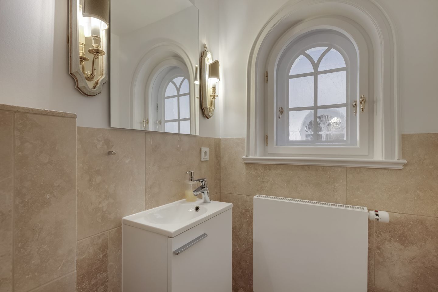 A bathroom with a white sink, a mirror, and a window with a view of a snowy landscape.