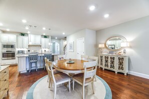 A spacious kitchen with white cabinets, a central island, and a dining area with a round table and chairs.