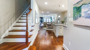 A spacious kitchen with a central island, wooden flooring, and a staircase leading to another level. - Swim, Hike & Chill: Spacious Ocean View Townhome! (Ocean View)