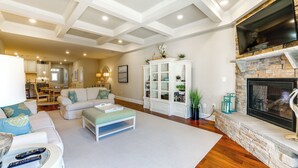 A spacious living room with a fireplace, a white cabinet, and a dining area in the background. - Swim, Hike & Chill: Spacious Ocean View Townhome! (Ocean View)