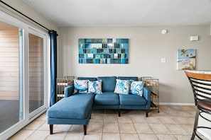 Relax in this stylish living room with a comfortable sofa, abstract art, and a sliding door to an outdoor space.
