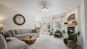 Un salon moderne doté d’une grande horloge ronde, d’une cheminée et offrant une vue sur l’extérieur.