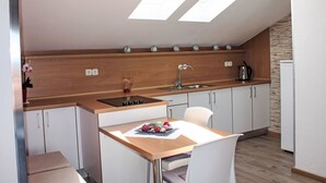 A modern kitchen with skylights, a dining area with a table and chairs, and a kitchen island. - Villa Silvia by Interhome (Makarska)
