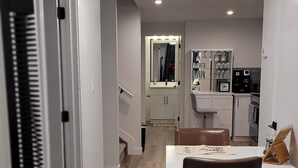 A modern kitchen with white cabinets, a dining area with a table and chairs, and a visible refrigerator. - Your Elegant Escape | Newly Built Prescott Private Suite (Spruce Grove)