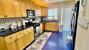 A modern kitchen with wooden cabinets, a black countertop, and a blue floor.