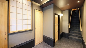 A hallway with a wooden door, a sliding glass door, and a staircase. - Ayanishiki Shimabara-Omon Residence (Kyoto)
