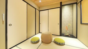 A traditional Japanese room with tatami flooring, a low wooden table, and two green cushions. - Ayanishiki Shimabara-Omon Residence (Kyoto)