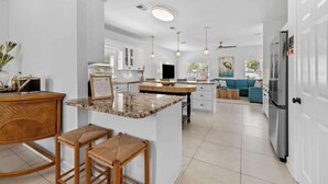 A modern kitchen with white cabinets, a granite island, and a dining area with bar stools.