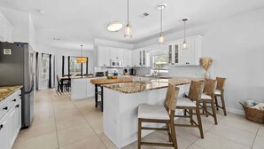 A modern kitchen with white cabinets, a central island, and pendant lighting.