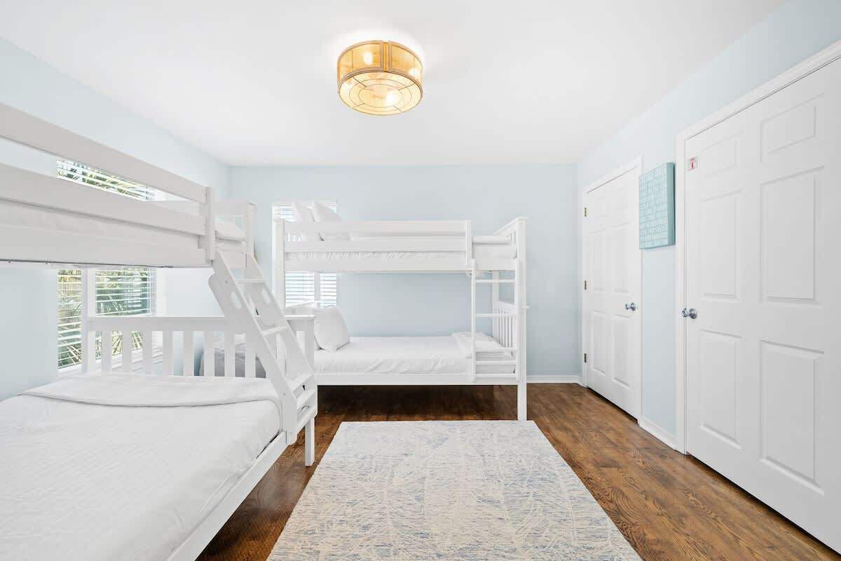 A room with bunk beds, a white door, and a ceiling light fixture.