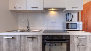 Una cocina moderna con armarios blancos, un lavamanos de acero inoxidable, un microondas integrado y un lavavajillas.