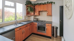 Een moderne keuken met houten kastjes, een gasfornuis, een spoelbak en een groot raam.