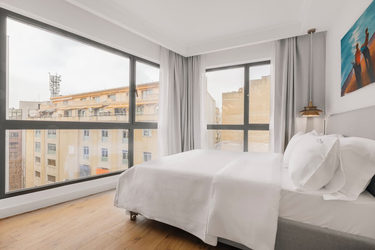 Ein Hotelzimmer mit großem Fenster, einem Bett und einem Gemälde an der Wand.