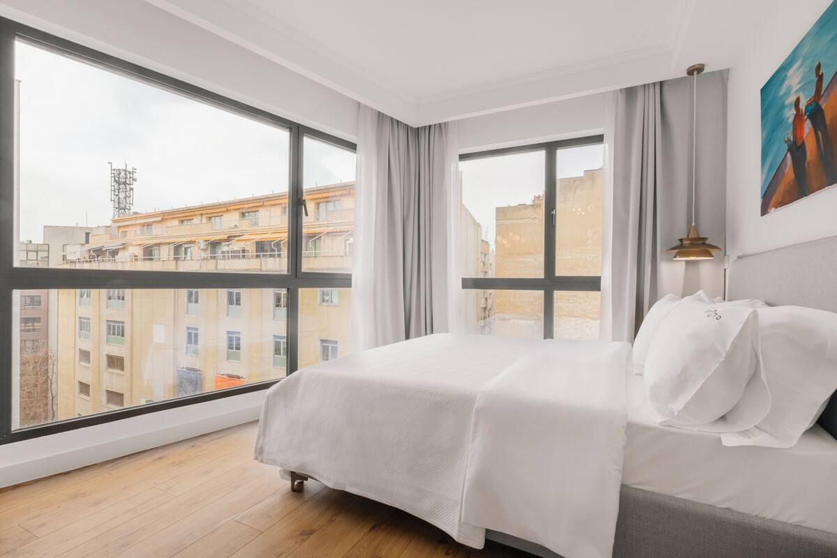 Un cuarto de hotel con un ventanal grande, una cama y un cuadro en la pared.