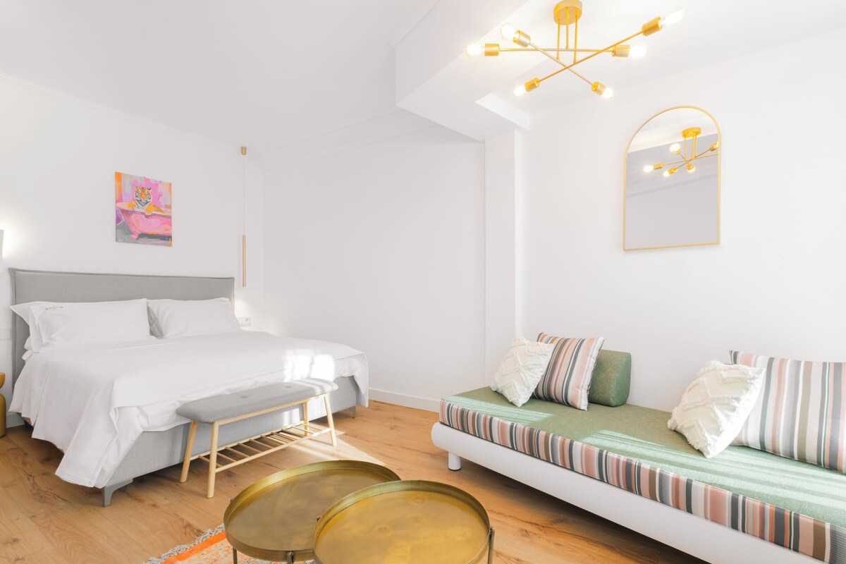Une chambre à coucher moderne avec un lit, un banc, un canapé et un tableau accroché au mur.