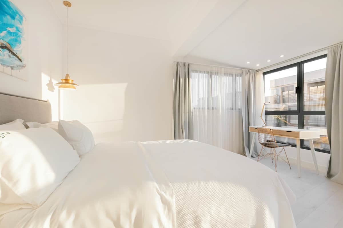 Ein Hotelzimmer mit einem großen Bett, einem Schreibtisch und Blick auf die Stadt.
