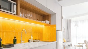 A modern kitchen with white cabinets, a yellow backsplash, and a built-in microwave. - Ototo Luxury Living (Thessaloniki)