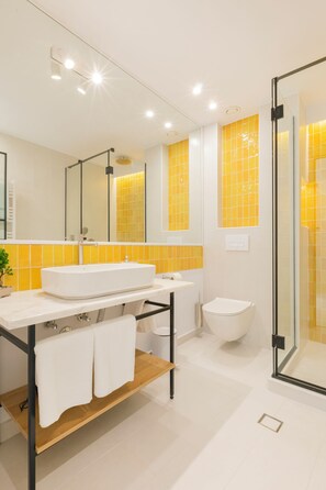 Une salle de bain moderne avec un lavabo, un miroir et des toilettes blancs, ainsi qu’une douche à parois de verre.