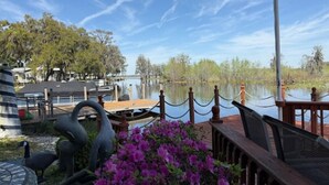 A lakeside view with a dock, boats, and a wooden deck with a railing. - The workshop room @ Bamboo house (Hernando)