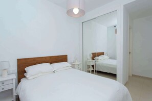 Relax in a spacious room with a large bed, bedside tables, and a full-length mirror.