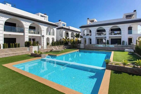 Guests can enjoy a refreshing swim in the central pool surrounded by a lush lawn.