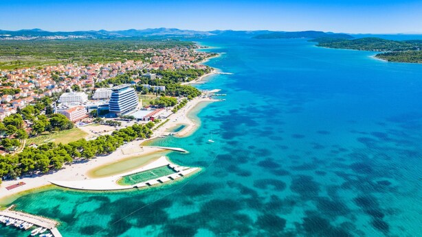 An aerial view of a coastal town with a marina, clear blue waters, and a mix of residential and commercial buildings. - Villa Claudio with private Pool, Vodice, Croatia (Vodice)